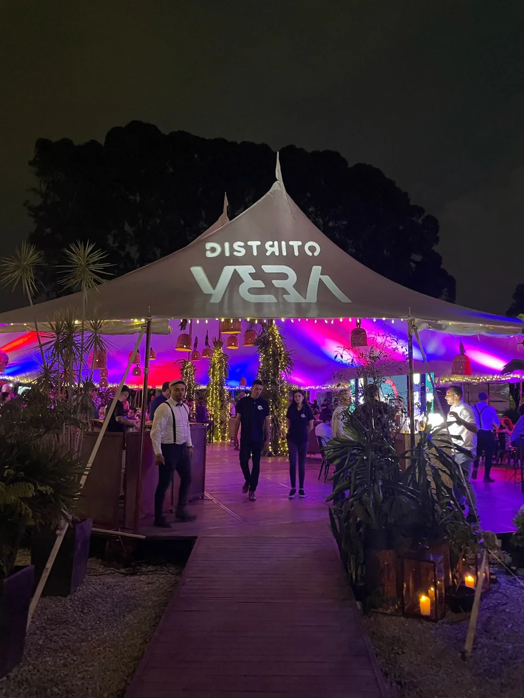 Distrito VERA: night event under a lit tent, with staff at the entrance